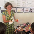 A woman stands at the front of a classroom holding period products.